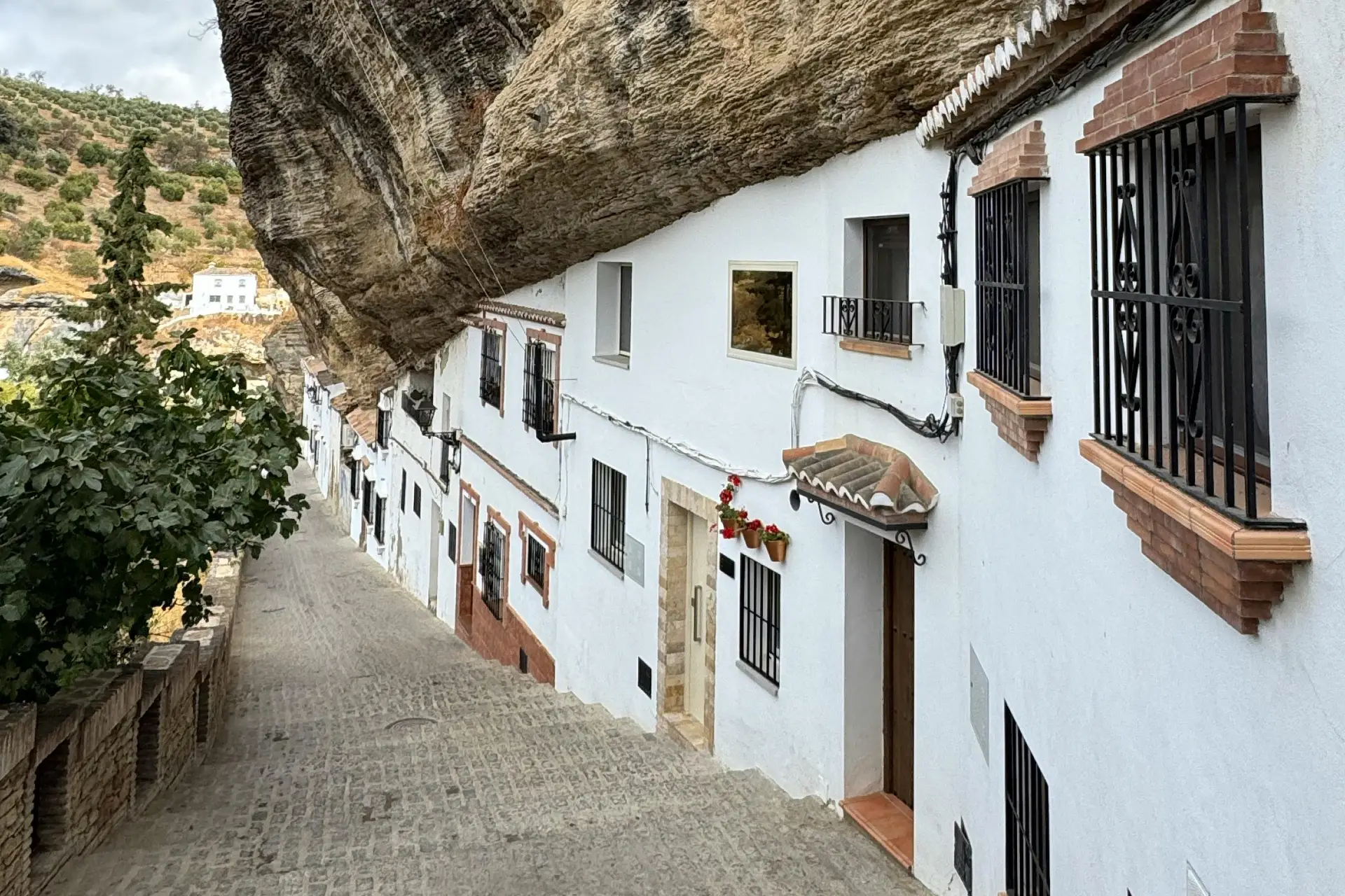 The Spain Road Trip 4 Scenic view of white houses under a rock overhang in Setenil de las Bodegas, Spain. - Photo by Petra Nesti from Pexels: https://www.pexels.com/photo/unique-street-under-rock-in-setenil-de-las-bodegas-34382966/