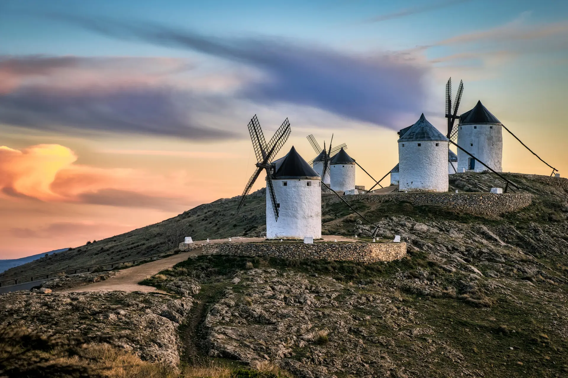 The Spain Road Trip 2 Stunning view of historic Consuegra windmills at sunset in Toledo, capturing the serene Spanish landscape - Photo by Juan Luis Secø from Pexels: https://www.pexels.com/photo/consuegra-windmills-castilla-la-mancha-spain-22880902/