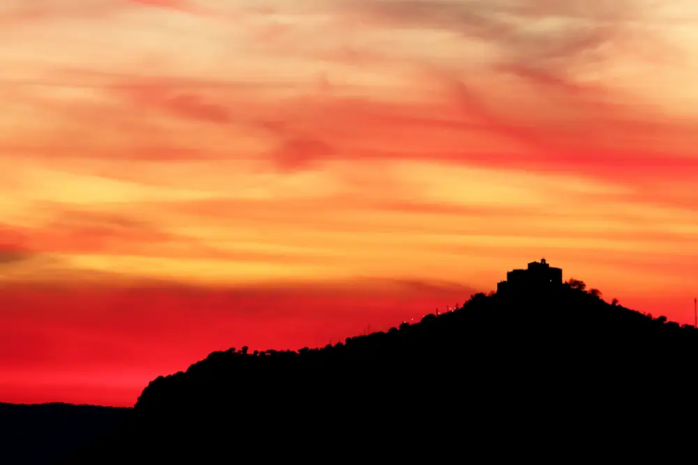October in Andalucia 1 sunset over Sierra Morena with building on ridge and trees in silhouette against a red and orange sky