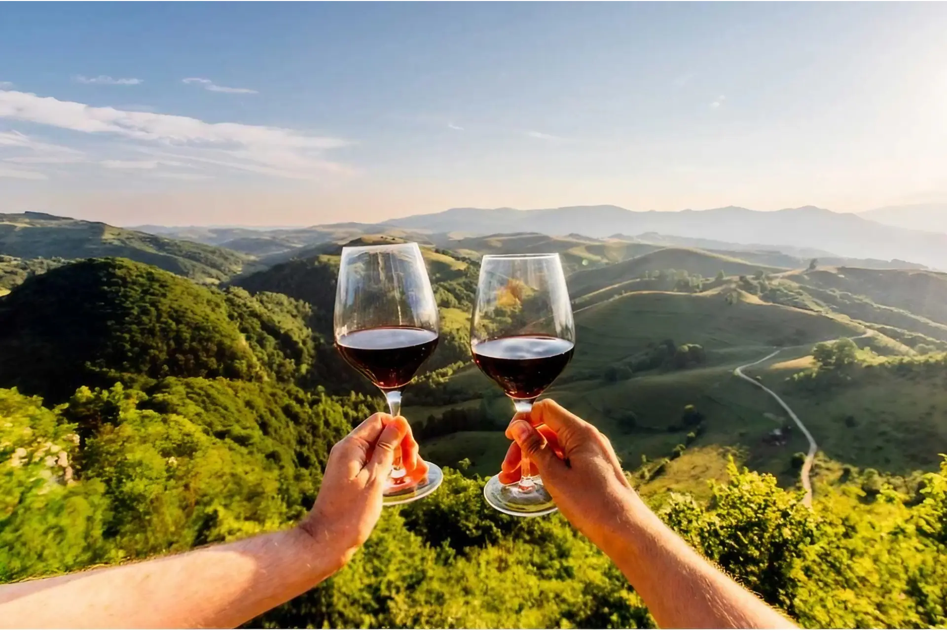 Wines of Malaga: Two hands clinking glasses of red wine in outdoor setting. Credit: Alexander Spatari / Moment via Getty Images